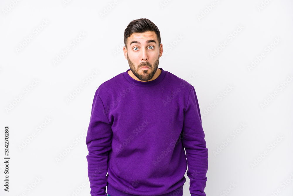 Young caucasian man against a white background isolated shrugs shoulders and open eyes confused. Young caucasian man against a white background isolated shrugs shoulders and open eyes confused.