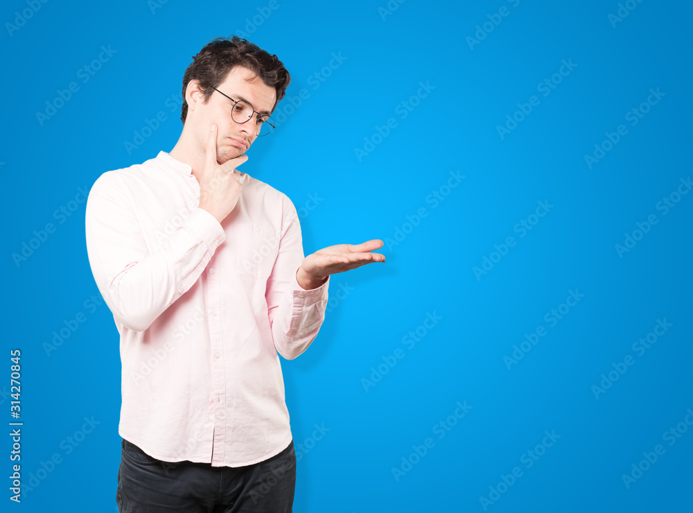 Doubtful young man holding something with his hand Doubtful young man holding something with his hand