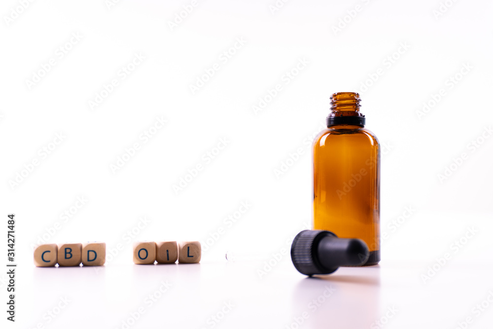 A small bottle with a dropper full of CBD oil or any other oil on white background - letters with A small bottle with a dropper full of CBD oil or any other oil on white background - letters with