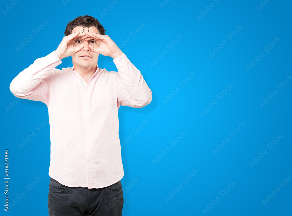 Happy young man using his hands like a binoculars Happy young man using his hands like a binoculars