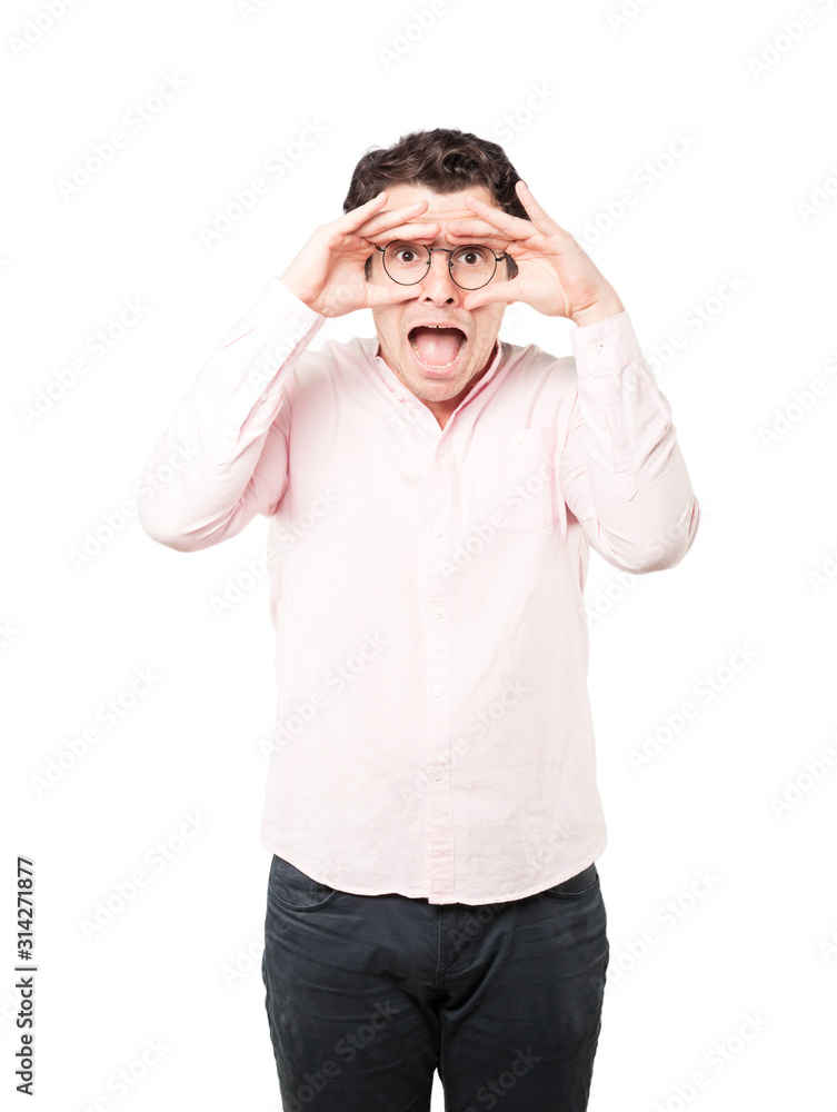 Amazed young man using his hands like a binoculars Amazed young man using his hands like a binoculars