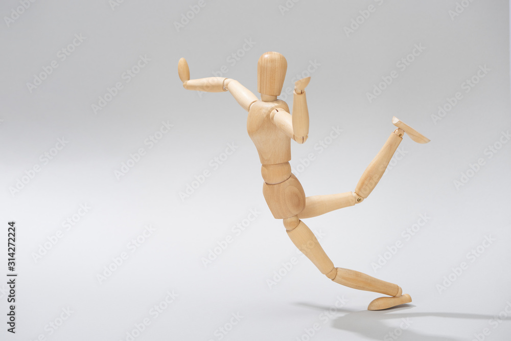 Wooden doll with raised hands and leg on grey background Wooden doll with raised hands and leg on grey background