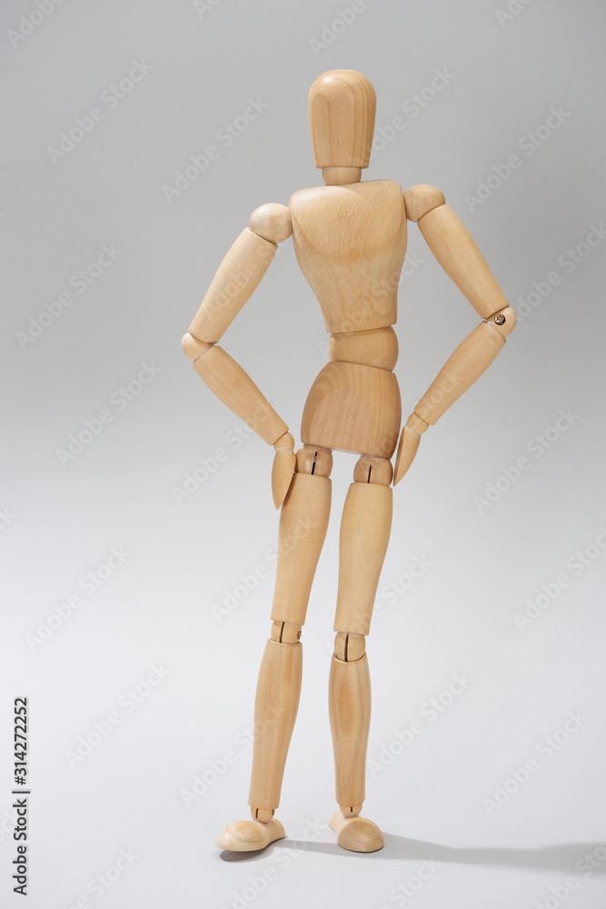 Wooden dummy with hands on hips on grey background Wooden dummy with hands on hips on grey background