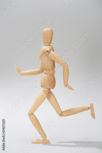 Wooden puppet with shadow on grey background