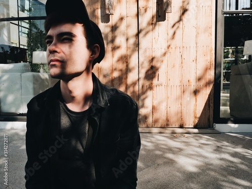 Portrait of mindful pensive handsome guy in black cap in sun light aqnd shade photo