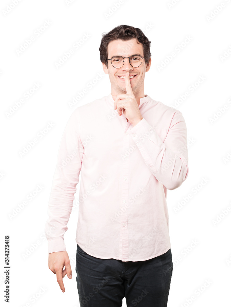 Happy young man asking for silence gesturing with his finger Happy young man asking for silence gesturing with his finger