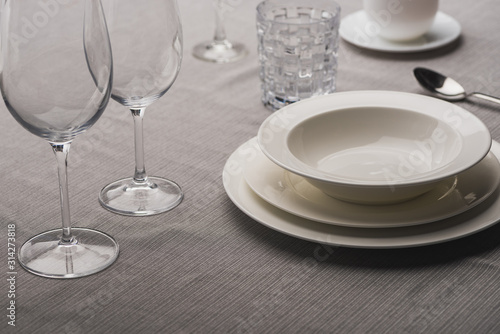 Serving tableware with wine glasses on grey tablecloth