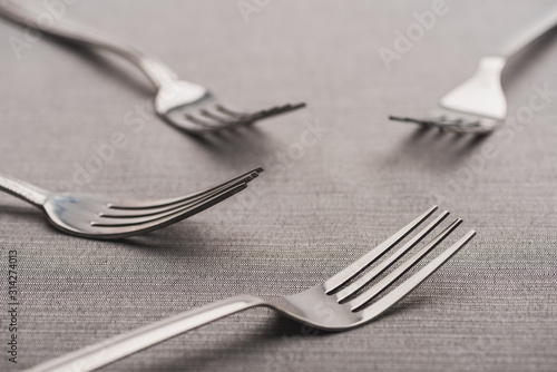 Selective focus of shiny forks of grey tablecloth