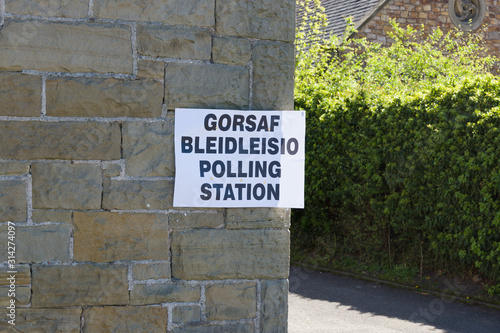 Polling station sign in Welsh and English language showing where people can go to cast their vote in an election in Wales UK