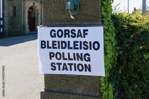 Polling station sign in Welsh and English language showing where people can go to cast their vote in an election in Wales UK