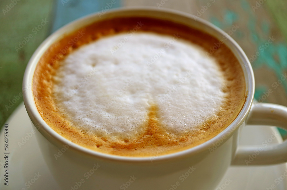 Closeup the texture of cappuccino coffee with milk foam on rustic wooden table Closeup the texture of cappuccino coffee with milk foam on rustic wooden table