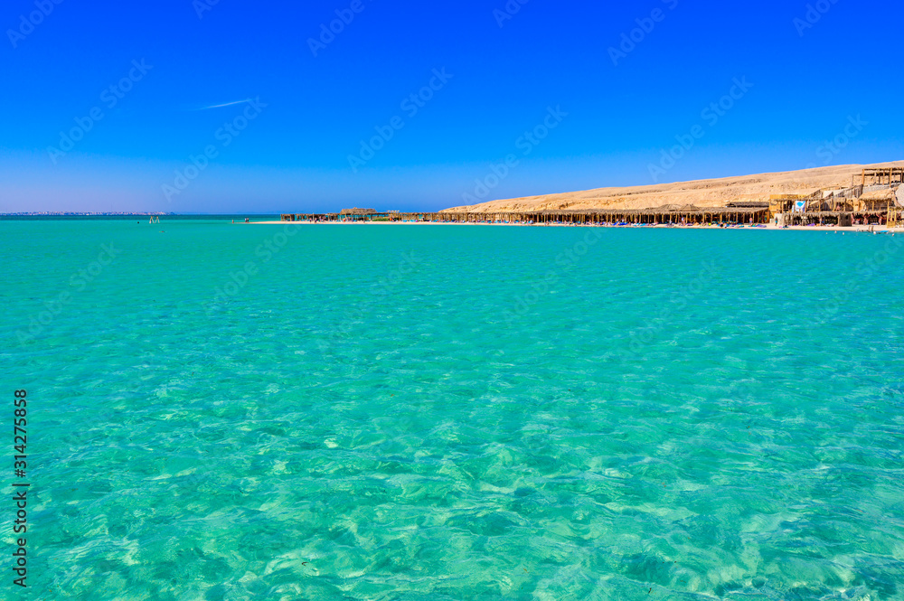 Orange Bay Beach with crystal clear azure water and white beach - paradise coastline of Giftun island, Mahmya, Hurghada, Red Sea, Egypt.