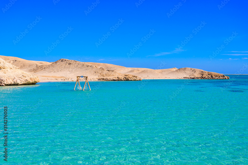 Orange Bay Beach with crystal clear azure water and white beach -  hammock in the water for relaxing - paradise coastline of Giftun island, Mahmya, Hurghada, Red Sea, Egypt.