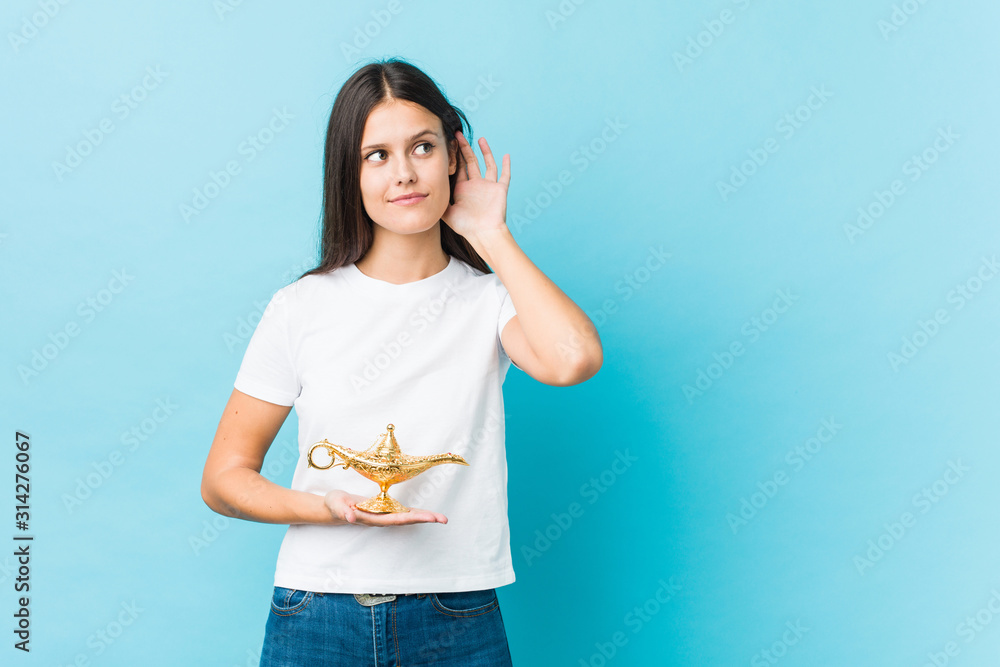 Young caucasian woman holding a magic lamp trying to listening a gossip. Young caucasian woman holding a magic lamp trying to listening a gossip.