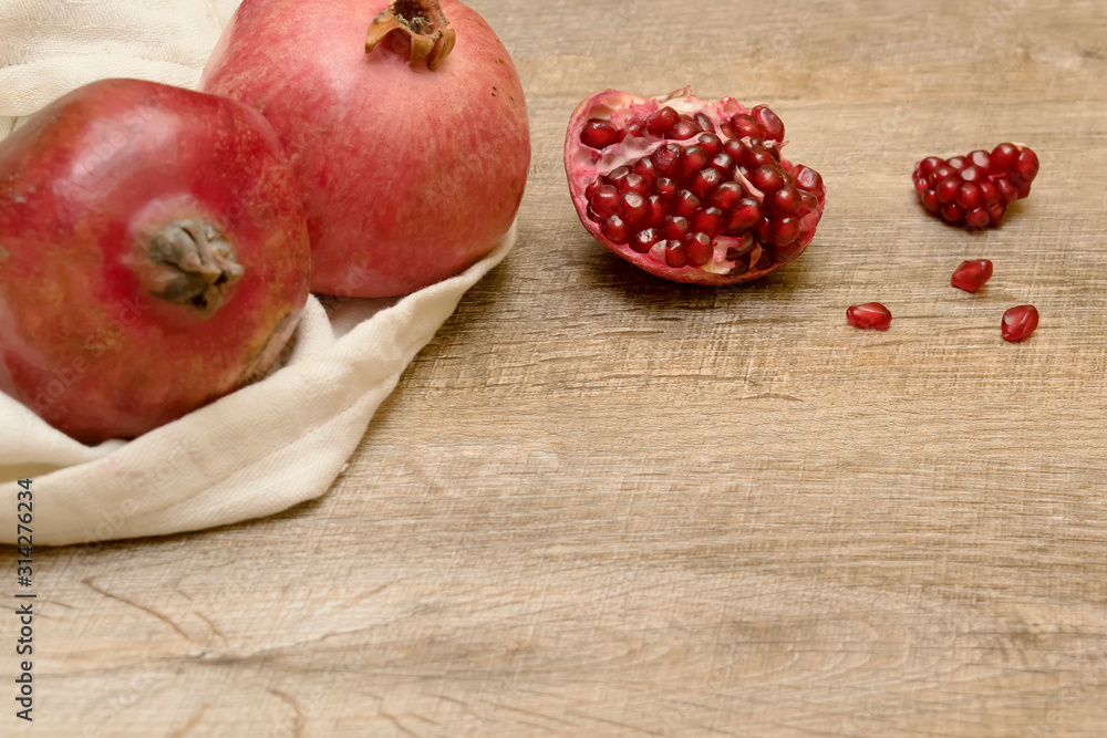 Ripe pomegranates in the white bag on the wooden table. Fruit fresh background. Ripe pomegranates in the white bag on the wooden table. Fruit fresh background.