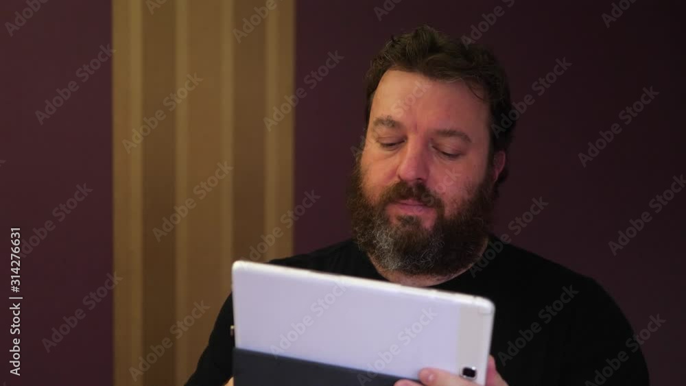 Portrait of bearded man while looking for something on the tablet Portrait of bearded man while looking for something on the tablet