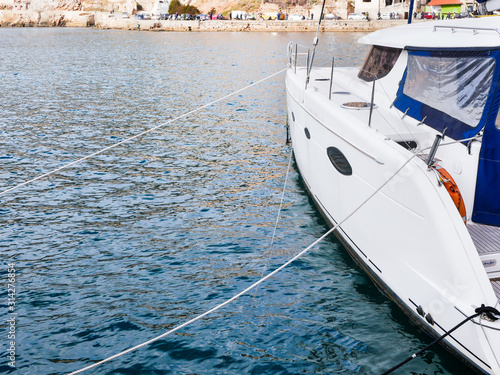 A beautiful catamaran yacht moored by ropes at the marina. Copy space. Close-up photo