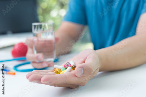 Serious man taking a pill standing at home