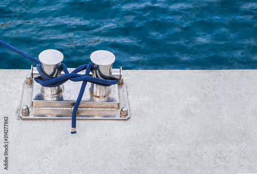 Knecht mount on a marina with a blue rope tied. Top view, close up, copy space photo