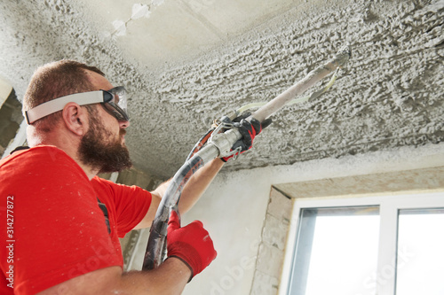 Obraz na płótnie Plasterer using sprayer machine putting plaster mortar on ceiling