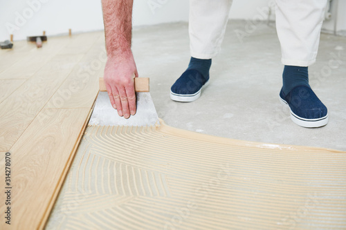 worker gluing wood parquet floor.
