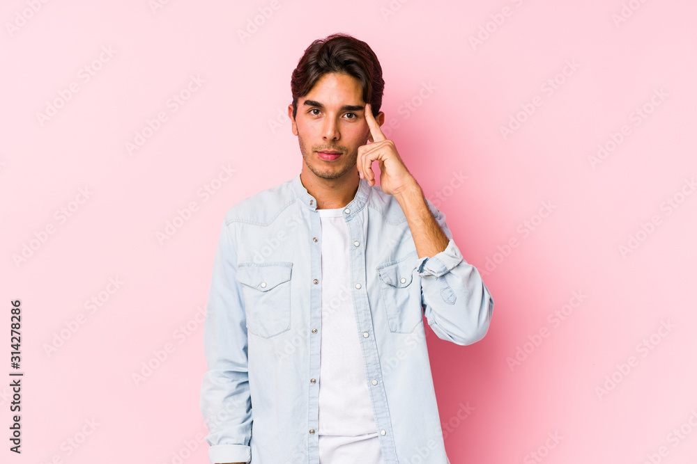 Young caucasian man posing in a pink background isolated pointing temple with finger, thinking, focused on a task. Young caucasian man posing in a pink background isolated pointing temple with finger, thinking, focused on a task.