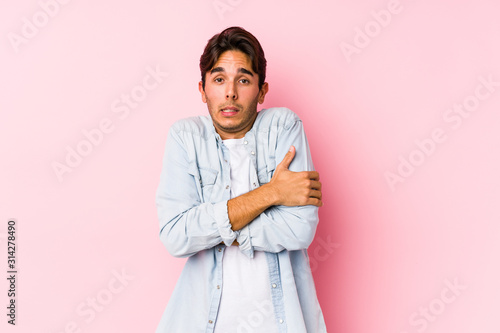 Young caucasian man posing in a pink background isolated going cold due to low temperature or a sickness. © Asier