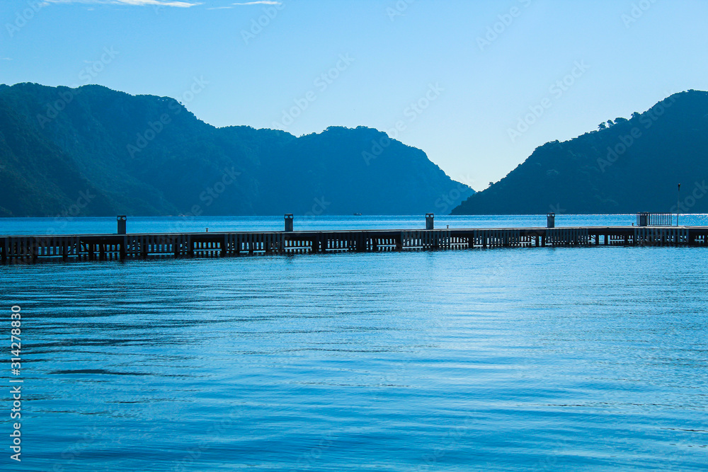 Holiday concept: pier on the sea, mountains on the horizon, selective focus