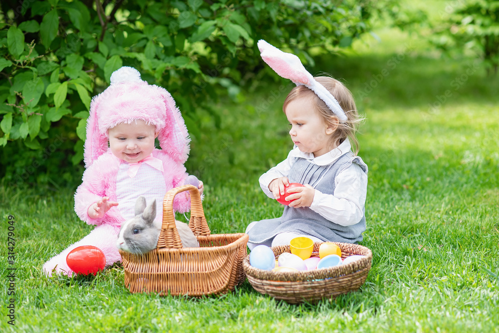 Children play with real rabbit. Laughing child at Easter egg hunt with pet  bunny. Little toddler