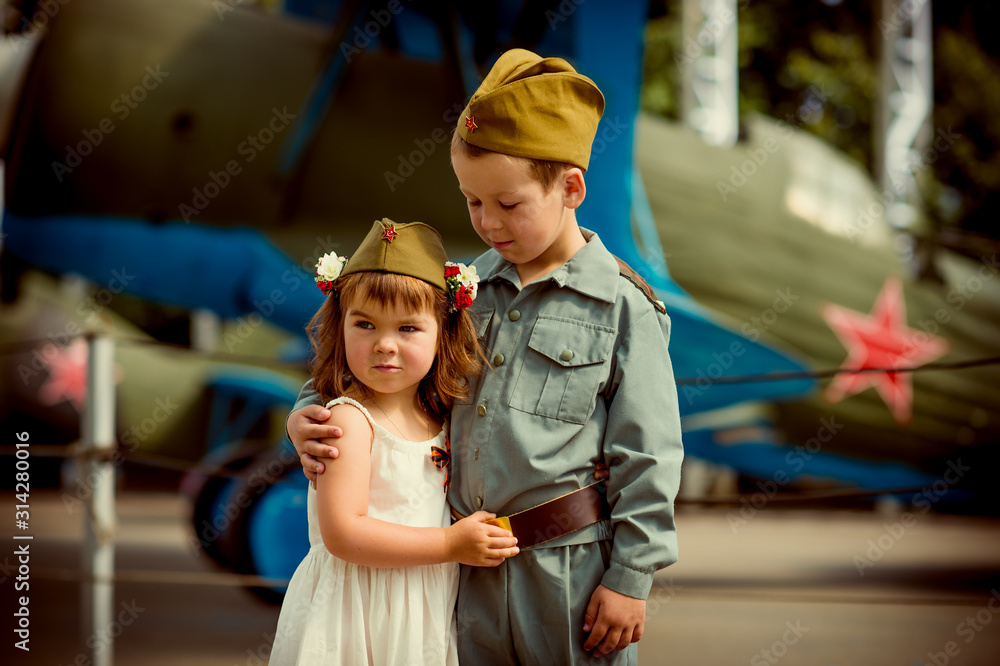 a boy of European appearance 6 years old in military uniform and a cute girl 4 years old in a white sundress, a reenactment of a meeting of a soldier with a bride, the theme of the great Patriotic war