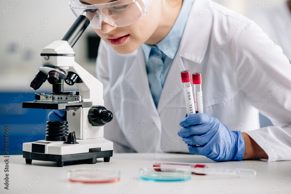 cropped view of genetic consultant using microscope and holding test tubes cropped view of genetic consultant using microscope and holding test tubes