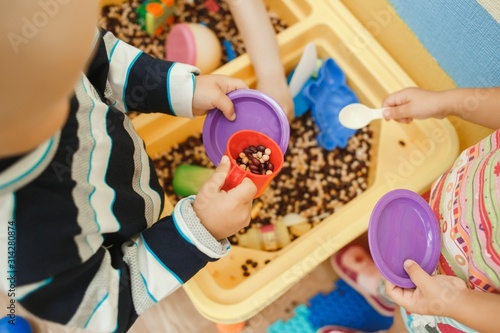 Children play educational games with a sensory bin in kindergarten photo