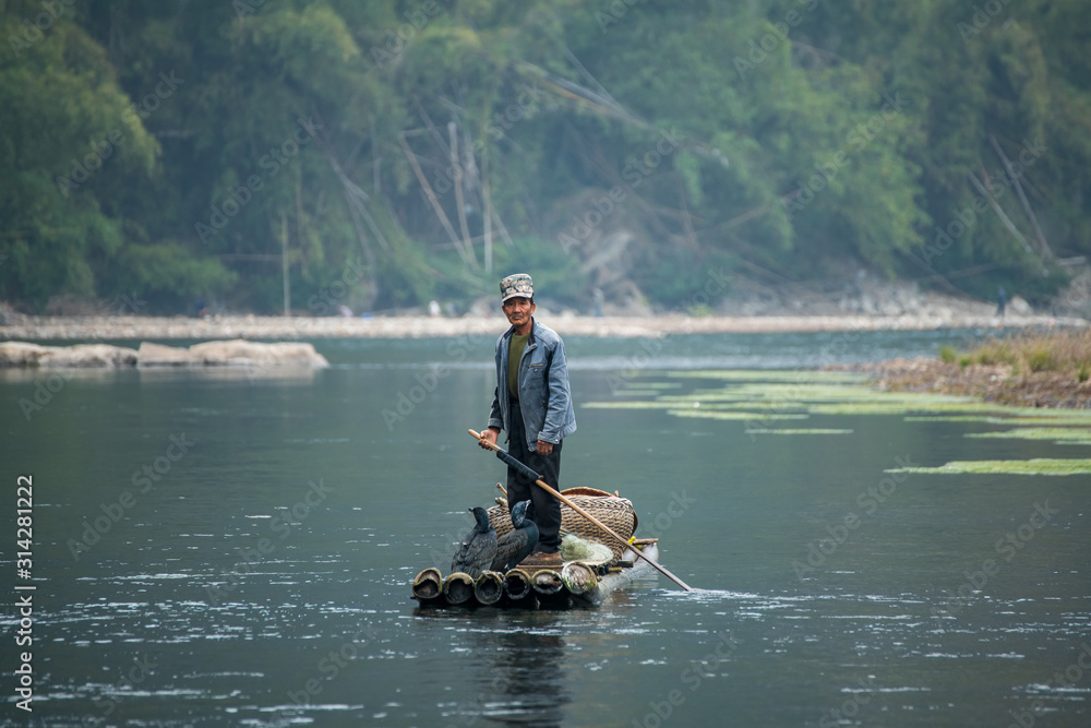 A fisherman and his cormorants on a bamboo raft in Guilin, China A fisherman and his cormorants on a bamboo raft in Guilin, China