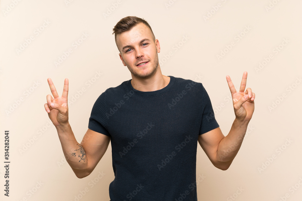 Young handsome blonde man over isolated background showing victory sign with both hands Young handsome blonde man over isolated background showing victory sign with both hands