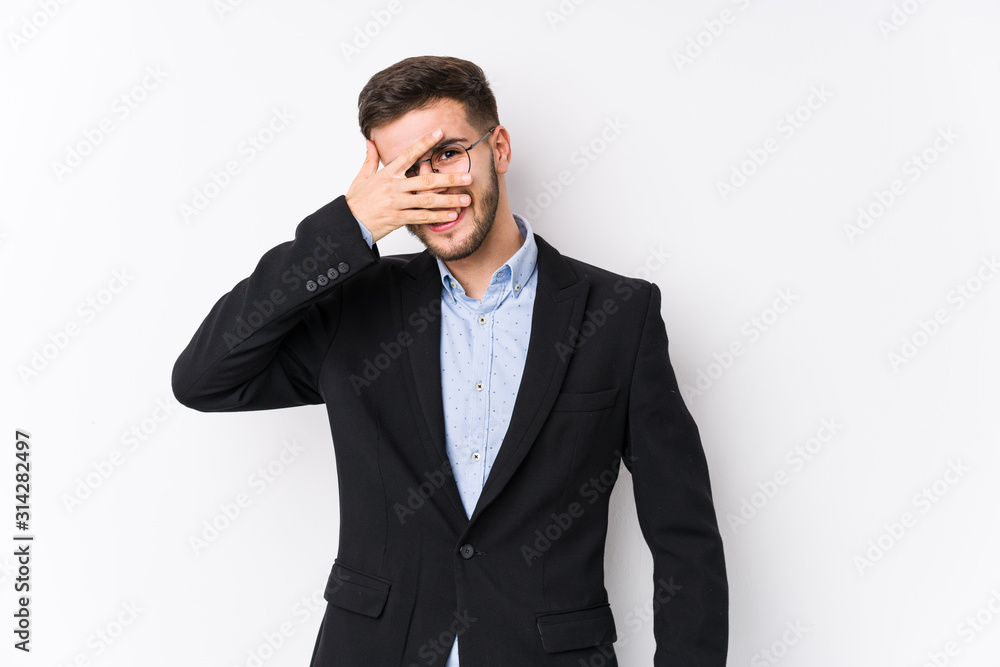 Young caucasian business man posing in a white background isolated Young caucasian business man blink at the camera through fingers, embarrassed covering face. Young caucasian business man posing in a white background isolated Young caucasian business man blink at the camera through fingers, embarrassed covering face.