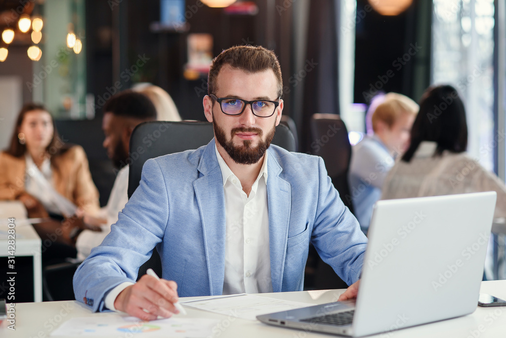 Close up handsome confident bearded office manager in business suit works with laptop at the office room. Close up handsome confident bearded office manager in business suit works with laptop at the office room.