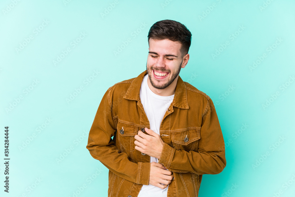 Young handsome man laughs happily and has fun keeping hands on stomach. Young handsome man laughs happily and has fun keeping hands on stomach.
