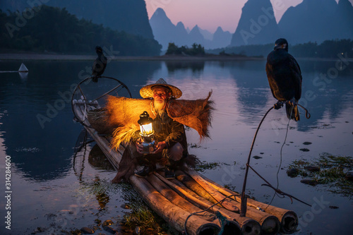 An old fisherman with a lamp on a raft after sunset photo