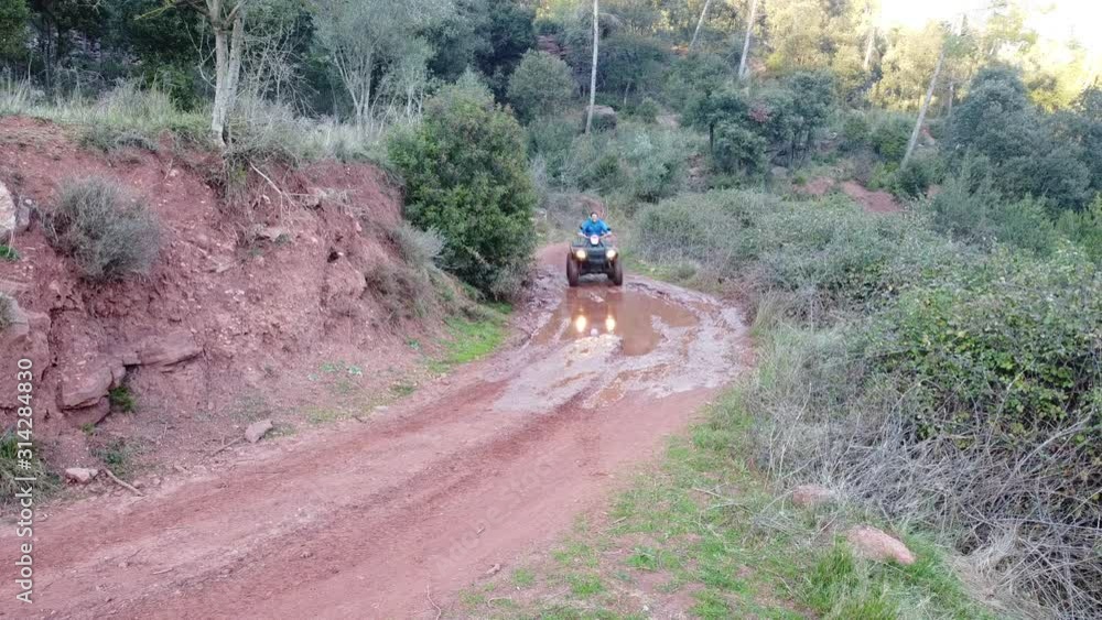 Man driving a quad going through a puddle