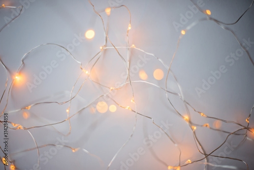 Blurry luminous warm white garland on the white background. New Year Christmas background.