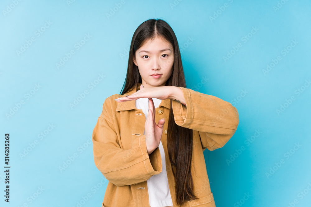 Young chinese woman posing in a blue background isolated showing a timeout gesture. Young chinese woman posing in a blue background isolated showing a timeout gesture.