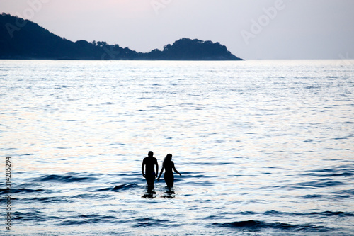 Couple swimming in sea at sunset.