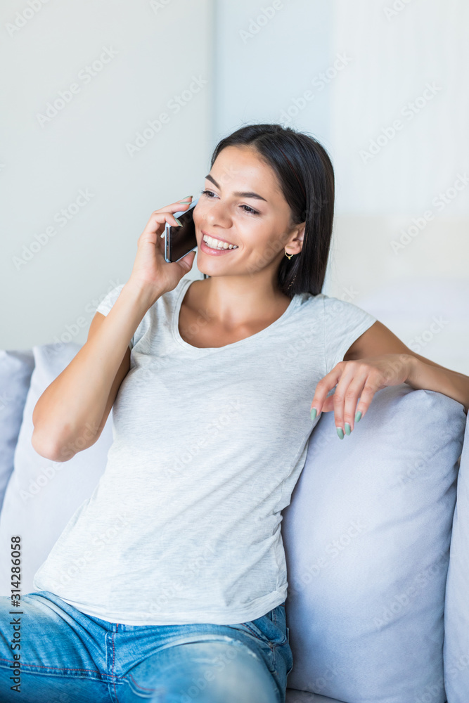 Young woman using mobile phone while sitting on couch at home Young woman using mobile phone while sitting on couch at home