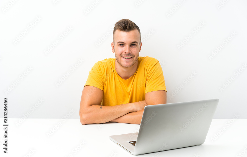 Young blonde man in a table with a laptop laughing Young blonde man in a table with a laptop laughing
