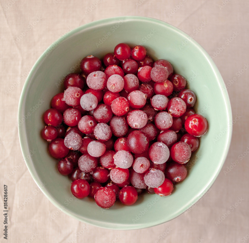 Frozen cranberry in green bowl close up. White linen cloth background view. Healthy eating concept Frozen cranberry in green bowl close up. White linen cloth background view. Healthy eating concept