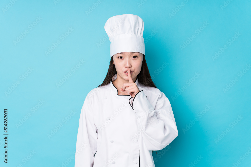 Young chinese chef woman isolated keeping a secret or asking for silence. Young chinese chef woman isolated keeping a secret or asking for silence.