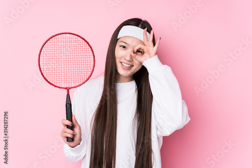 Young chinese woman playing badminton isolated excited keeping ok gesture on eye. © Asier