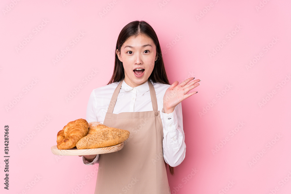 Young chinese baker woman isolated surprised and shocked. Young chinese baker woman isolated surprised and shocked.