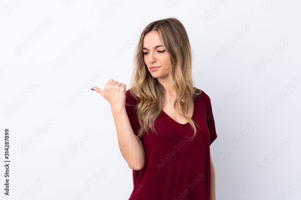 Young woman over isolated white background unhappy and pointing to the side Young woman over isolated white background unhappy and pointing to the side