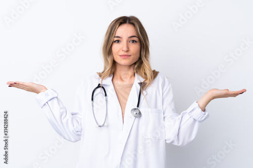 Young woman over isolated white background wearing a doctor gown and having doubts